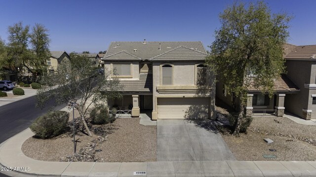 view of front of home with stucco siding, driveway, a tile roof, and a garage