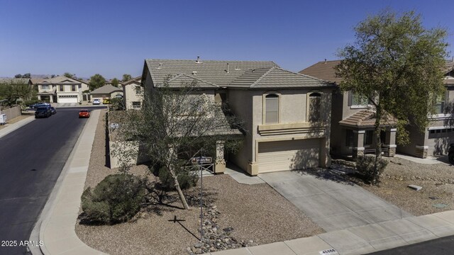 view of front of property with stucco siding, driveway, a tile roof, a residential view, and an attached garage