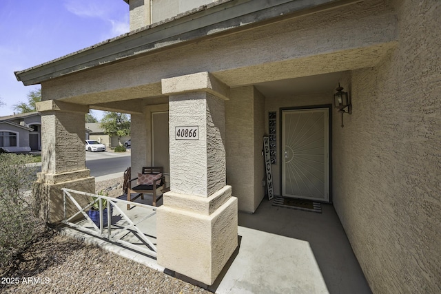doorway to property with stucco siding and covered porch