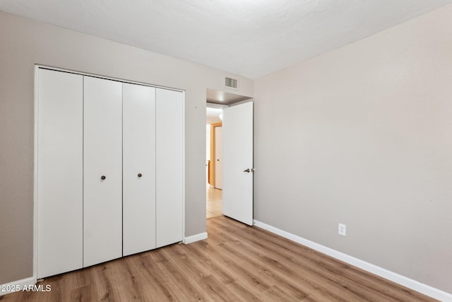 unfurnished bedroom featuring light hardwood / wood-style floors and a closet