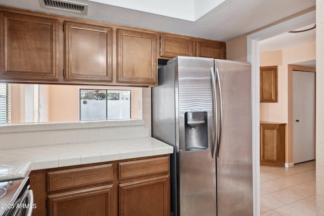 kitchen with light tile patterned floors, tile counters, and stainless steel appliances