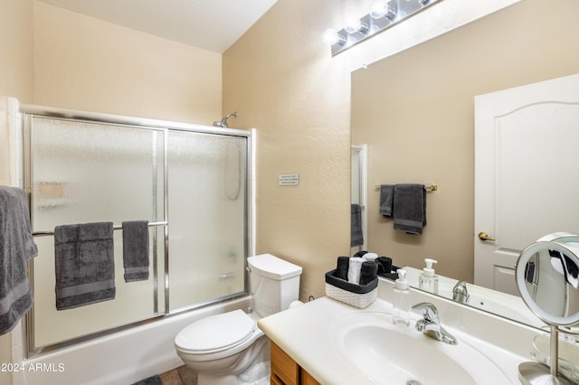 bathroom featuring vanity, bath / shower combo with glass door, and toilet
