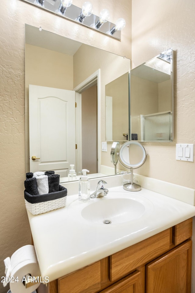 bathroom featuring vanity, a textured wall, and toilet