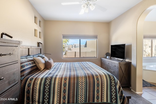 bedroom with arched walkways, a ceiling fan, and tile patterned flooring
