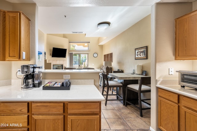 kitchen featuring a peninsula, open floor plan, light countertops, a tile fireplace, and light tile patterned floors