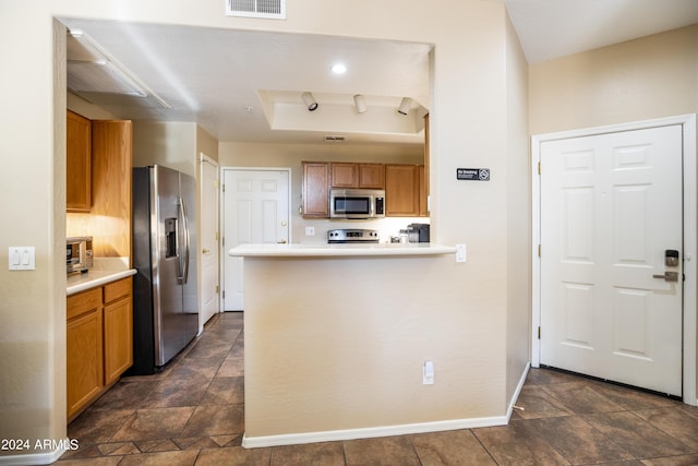 kitchen featuring baseboards, a raised ceiling, appliances with stainless steel finishes, and brown cabinets