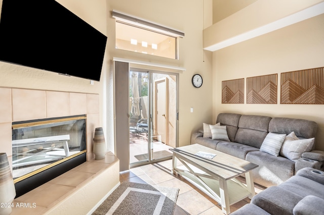 living area featuring a towering ceiling, light tile patterned floors, and a fireplace