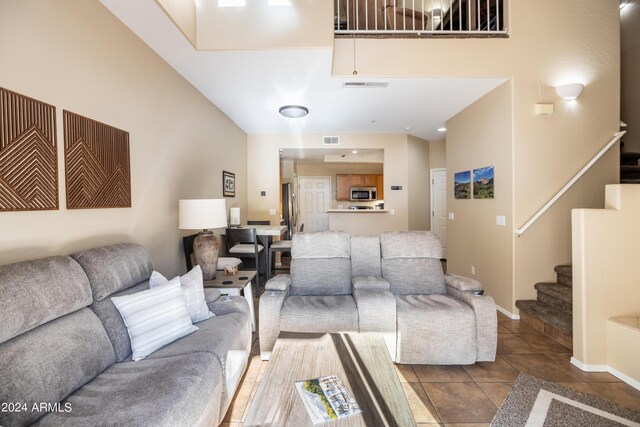 tiled living room with visible vents, baseboards, a towering ceiling, and stairway