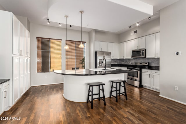 kitchen with appliances with stainless steel finishes, a breakfast bar, white cabinetry, and an island with sink