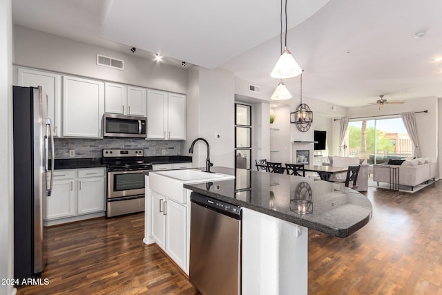 kitchen featuring white cabinetry, appliances with stainless steel finishes, a breakfast bar, and a center island with sink