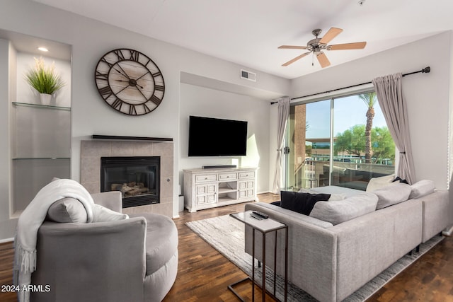 living room with dark wood-type flooring, a tile fireplace, and ceiling fan