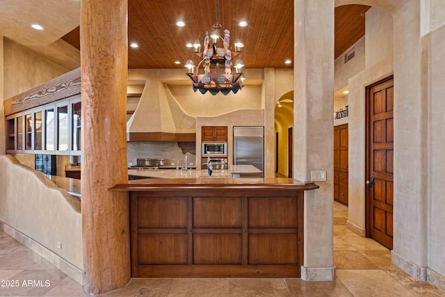 kitchen featuring arched walkways, custom range hood, decorative backsplash, wood ceiling, and built in appliances