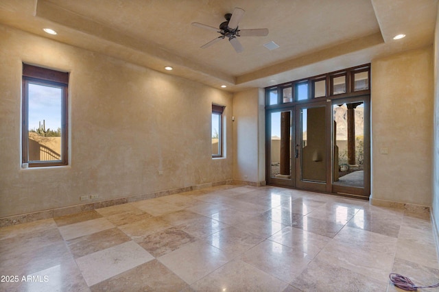 unfurnished room with a tray ceiling, recessed lighting, a ceiling fan, and baseboards