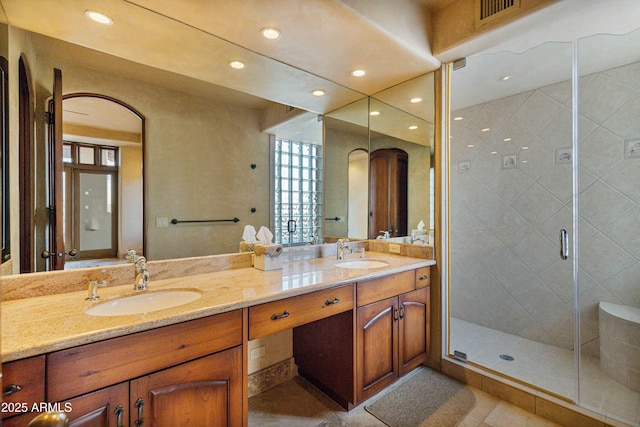 bathroom with double vanity, a stall shower, visible vents, and a sink