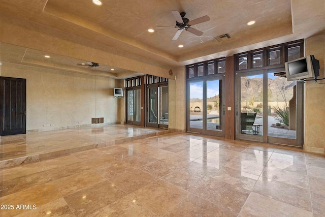 interior space featuring a ceiling fan, a raised ceiling, and visible vents