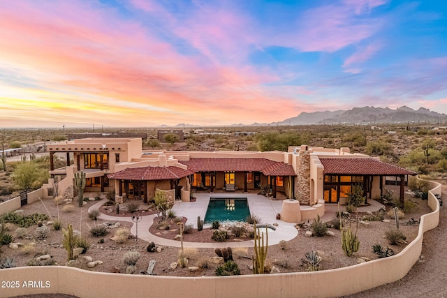 back of house featuring a tiled roof, a patio area, a mountain view, and stucco siding