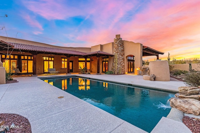 pool at dusk featuring a patio area and an outdoor pool