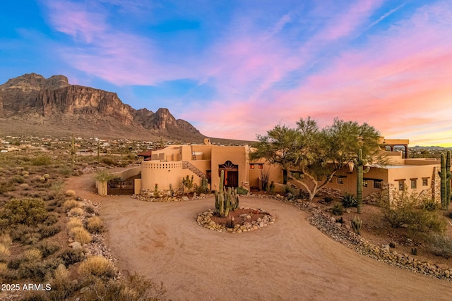 pueblo revival-style home with driveway, a mountain view, and stucco siding