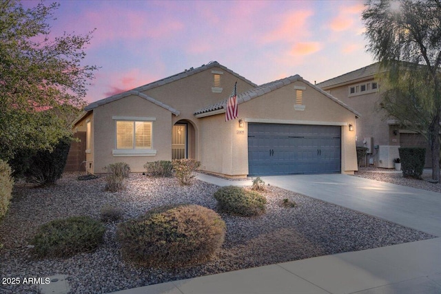 view of front of property with concrete driveway, an attached garage, a tiled roof, and stucco siding