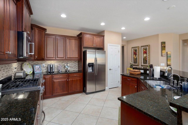 kitchen with appliances with stainless steel finishes, sink, backsplash, and dark stone counters