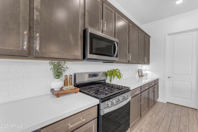 22634 E Roundup Way, Queen Creek, AZ 85142 - kitchen with stainless steel appliances, light countertops, tasteful backsplash, dark brown cabinets, and light wood-style flooring