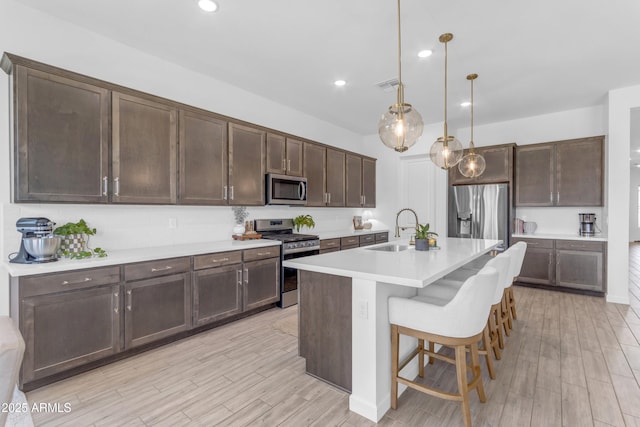 22634 E Roundup Way, Queen Creek, AZ 85142 - kitchen featuring appliances with stainless steel finishes, dark brown cabinetry, light wood finished floors, light countertops, and recessed lighting