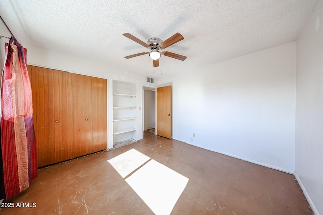 unfurnished bedroom with ceiling fan, a closet, concrete flooring, and a textured ceiling