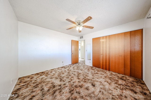 unfurnished bedroom with ceiling fan, carpet floors, a closet, and a textured ceiling