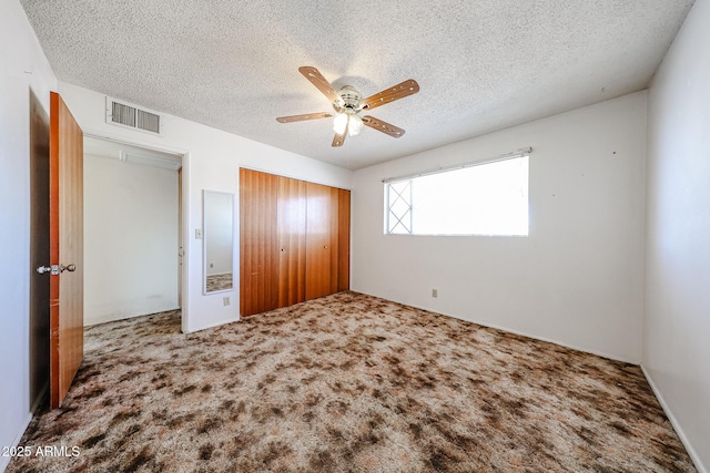 unfurnished bedroom with ceiling fan, a closet, a textured ceiling, and carpet flooring