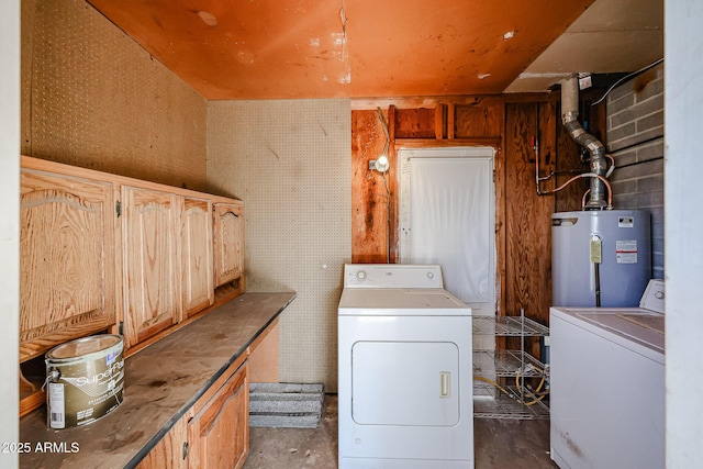 clothes washing area featuring washer and dryer, cabinets, and water heater