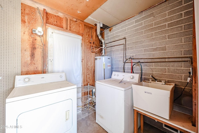 laundry room with water heater, sink, independent washer and dryer, and brick wall