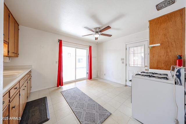 kitchen featuring sink, light tile patterned floors, white gas range oven, and ceiling fan