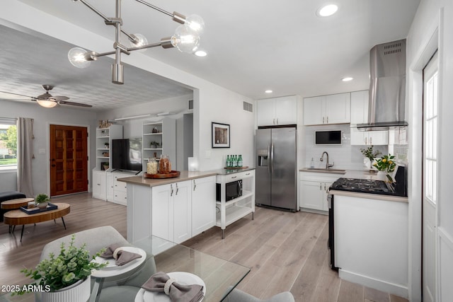 kitchen with visible vents, island exhaust hood, a sink, stainless steel appliances, and light wood-type flooring