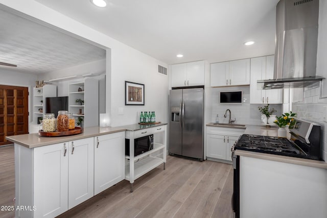 kitchen with light wood-style flooring, a sink, stainless steel appliances, white cabinets, and island range hood