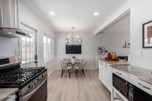 kitchen with tasteful backsplash, range hood, gas stove, light wood-style floors, and white cabinets