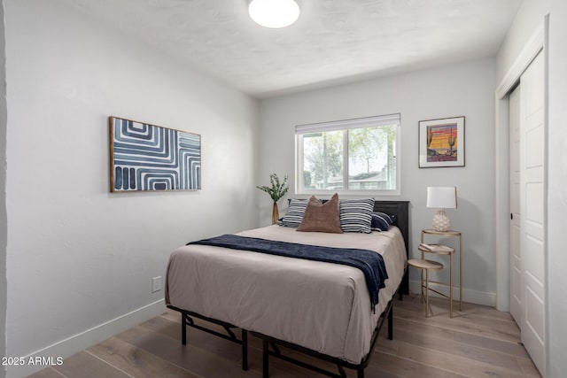 bedroom with a closet, baseboards, and wood finished floors