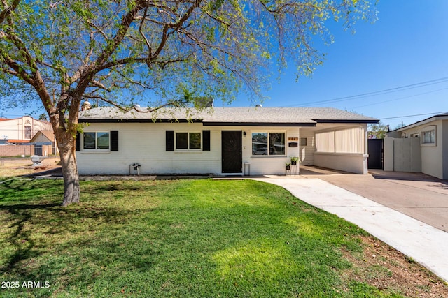 ranch-style home featuring an attached carport, fence, a front lawn, and driveway