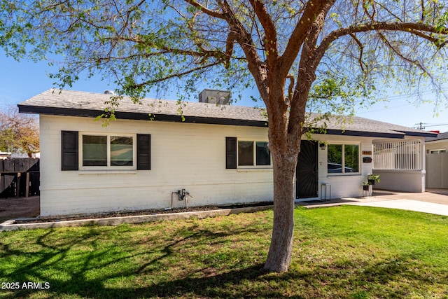 rear view of house with a patio area, a lawn, fence, and roof with shingles