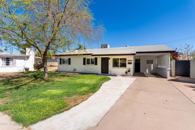 single story home featuring an attached carport, roof with shingles, concrete driveway, a front yard, and brick siding