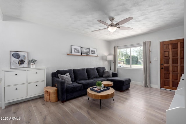 living area with ceiling fan, baseboards, and light wood-style flooring