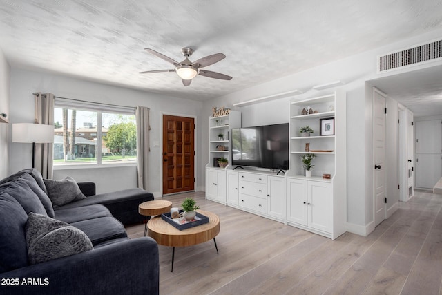 living area with light wood finished floors, visible vents, and ceiling fan