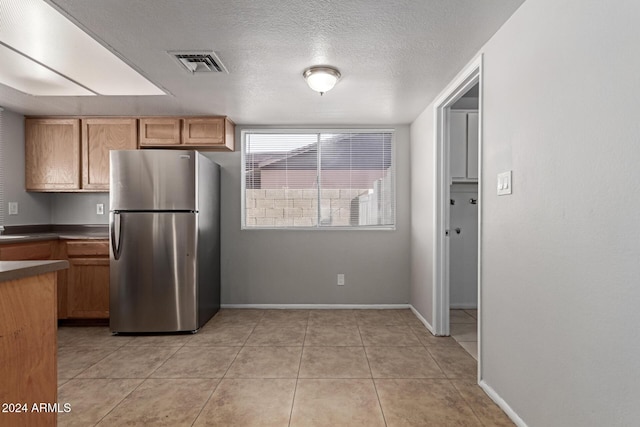 kitchen featuring stainless steel fridge, a textured ceiling, and light tile patterned floors