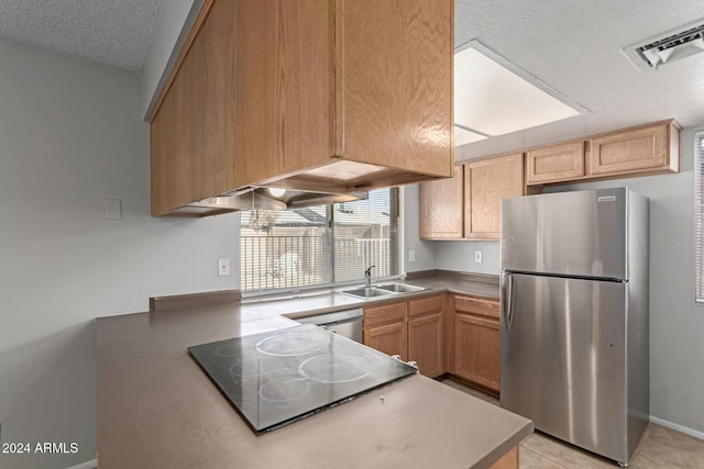 kitchen featuring a textured ceiling, light brown cabinets, sink, and stainless steel appliances