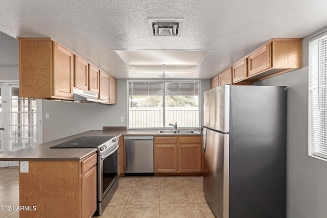 kitchen featuring kitchen peninsula, appliances with stainless steel finishes, light tile patterned floors, and sink