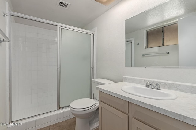 bathroom featuring toilet, vanity, tile patterned floors, and an enclosed shower