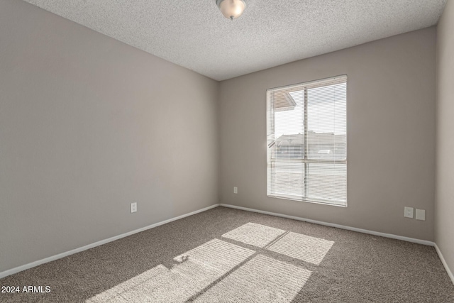 carpeted empty room featuring a textured ceiling