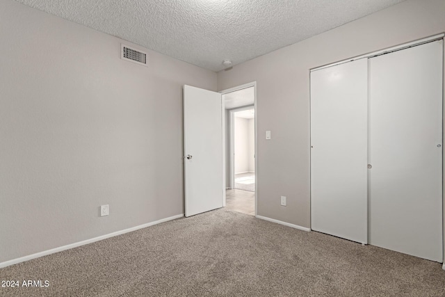 unfurnished bedroom with a textured ceiling, carpet floors, and a closet