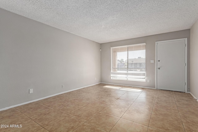 tiled empty room featuring a textured ceiling