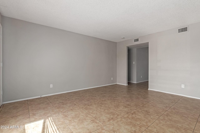 empty room featuring light tile patterned flooring and a textured ceiling