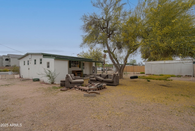 rear view of house with stucco siding, an outdoor hangout area, and fence